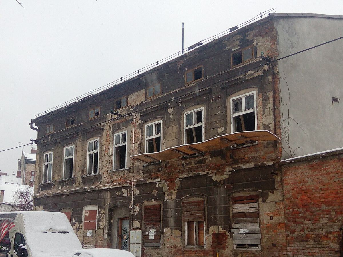 La maison de ville avant travaux, enduit tombé, briques à nu et fenêtres condamnées.