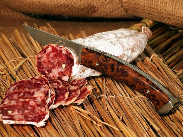 Saucisson sec entamé et tranché sur une planche, couteau à côté
