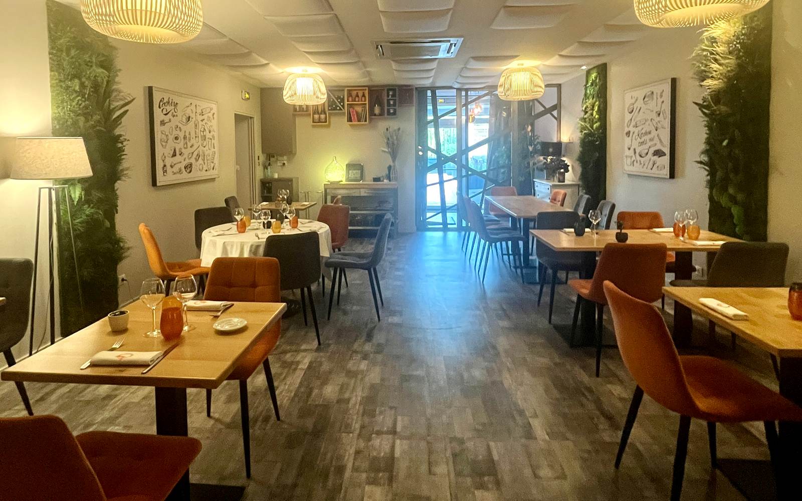Salle du restaurant, tables dressées sous des suspensions en bois clair