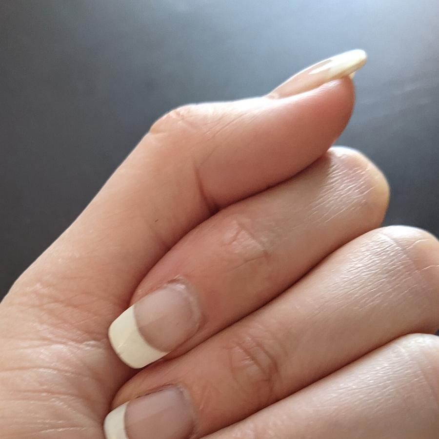 Main aux ongles en manucure française, cadrage serré sur les doigts