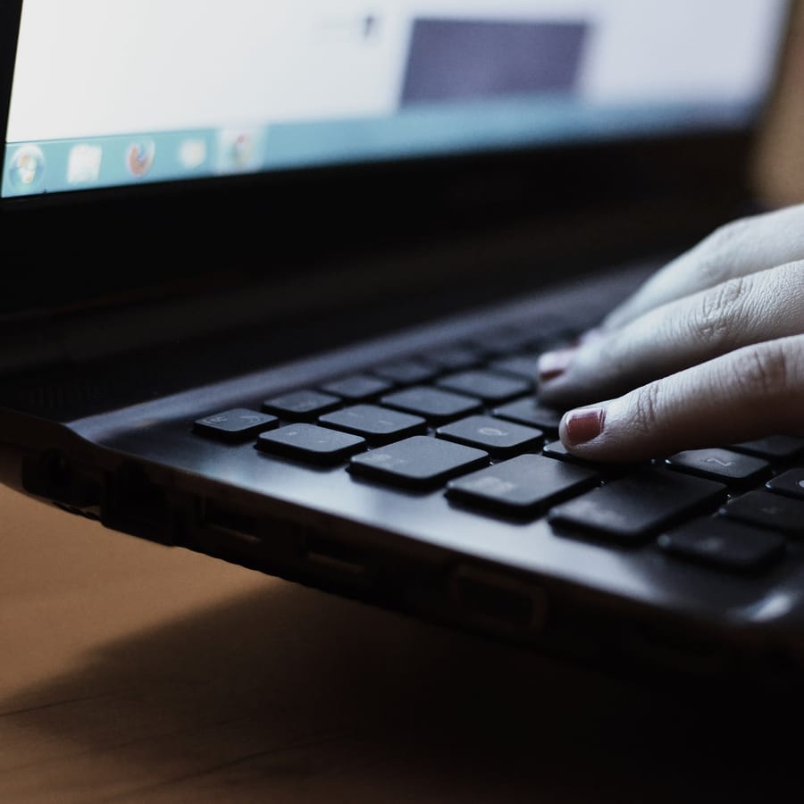 Mains posées sur le clavier d'un ordinateur portable, cadrage serré