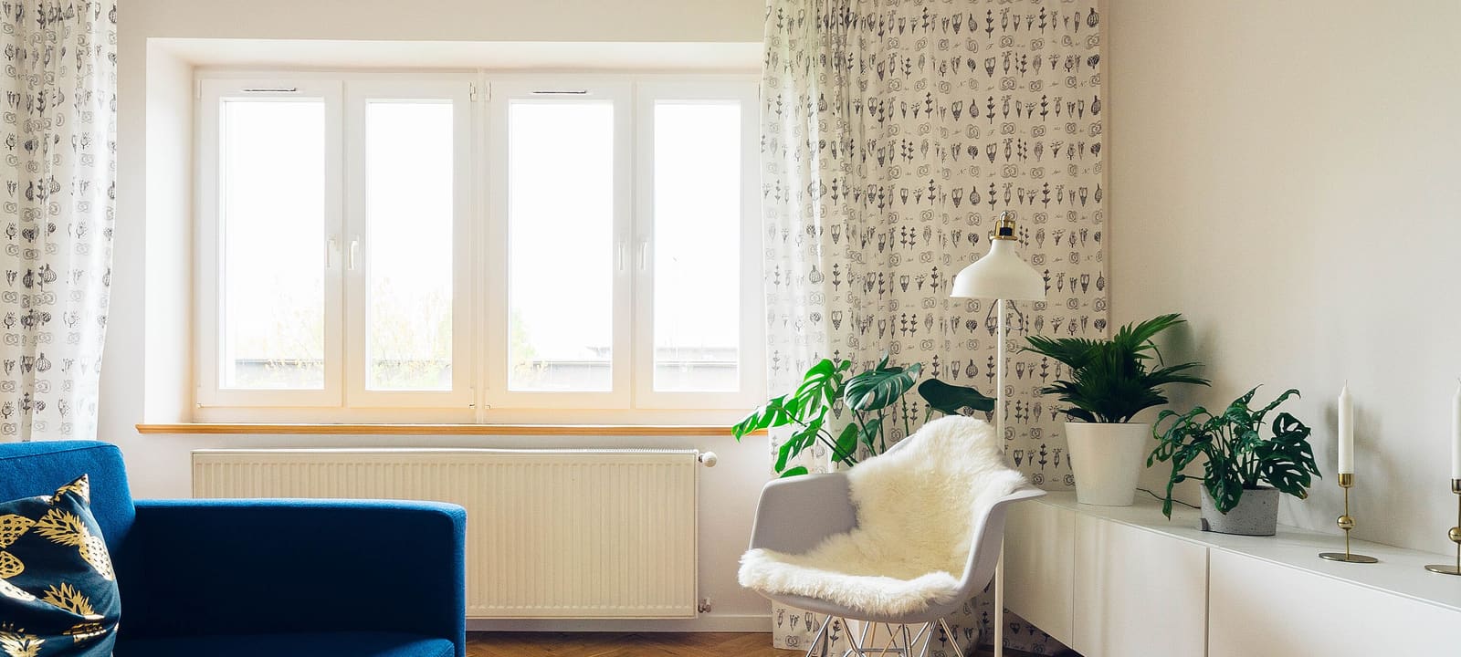 Séjour d'un appartement en plein jour, fenêtre ouverte sur la lumière, parquet, fauteuil et plantes vertes