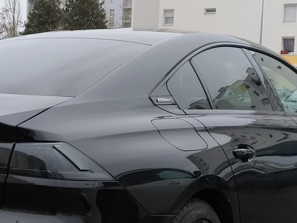 Flanc arrière d'une berline noire garée le long d'un trottoir