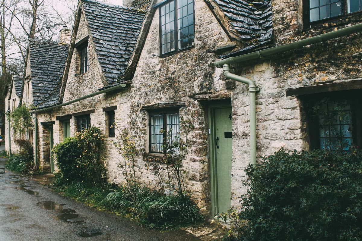 Maison de bourg en pierre, façade sur une ruelle, porte verte et haie taillée