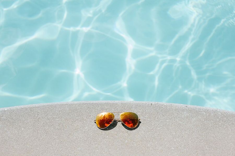 Paire de lunettes de soleil à verres miroir posée sur une margelle
