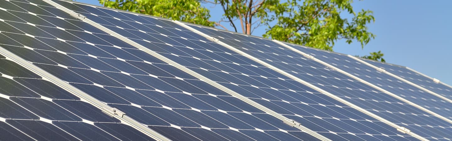 Rangée de modules photovoltaïques vus de près, cadres alignés sur une toiture inclinée