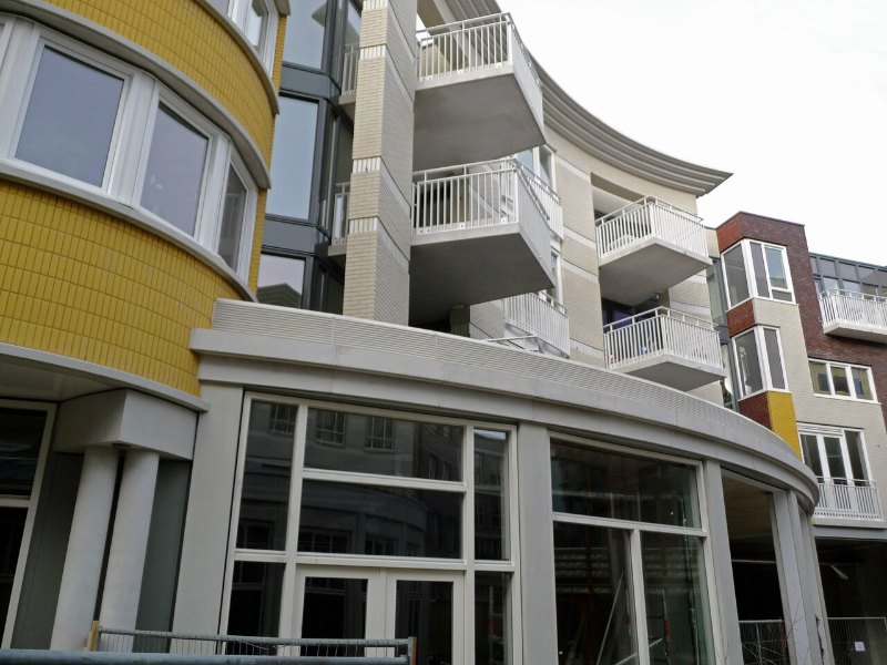 Immeuble de logements neuf livré, façade à balcons au-dessus des commerces du rez-de-chaussée.
