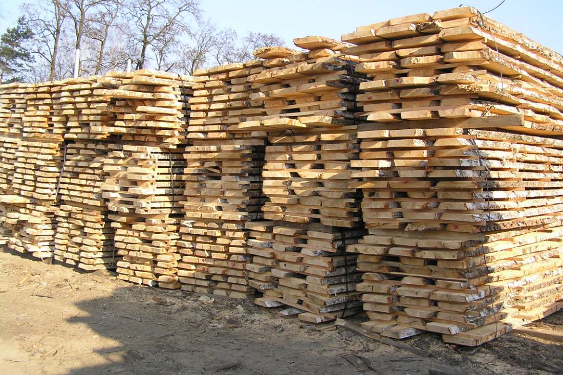 Piles de planches fraîchement sciées séchant à l'air libre, séparées par des baguettes de séchage.