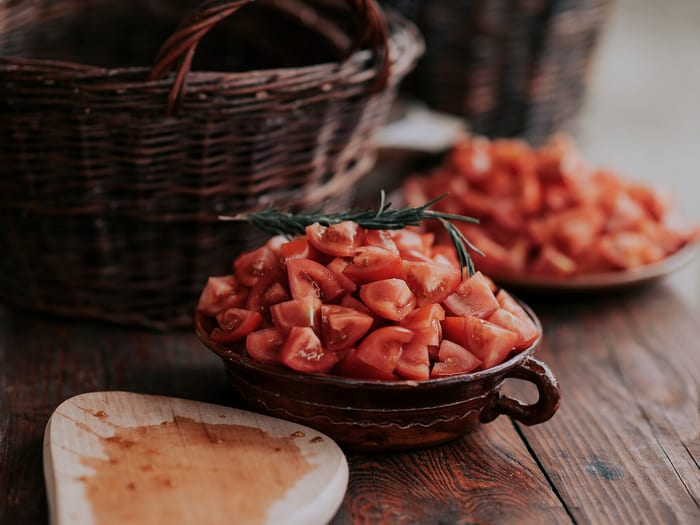Tomates lavées et coupées en morceaux dans des plats en terre