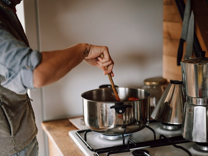 Cuisson d'une préparation de légumes remuée à la cuillère en bois dans une casserole