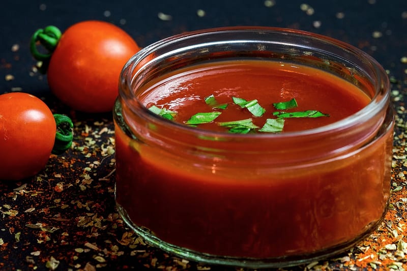 Bocal ouvert de sauce tomate au basilic, tomates entières autour