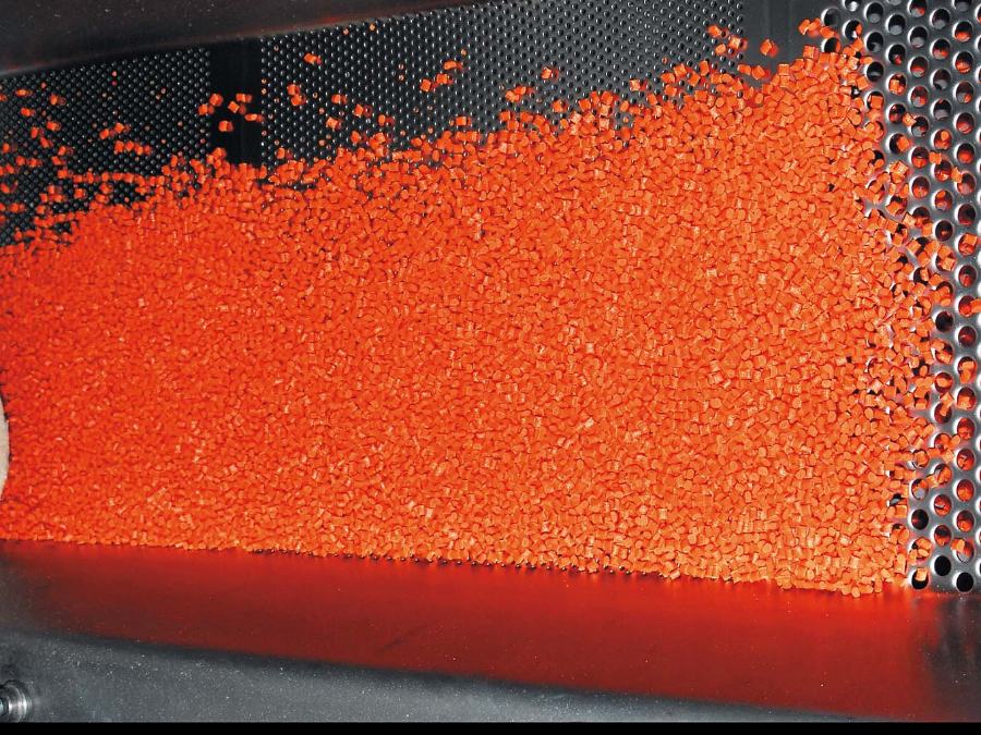 Granulés orange en mouvement dans une machine de dosage de colorant