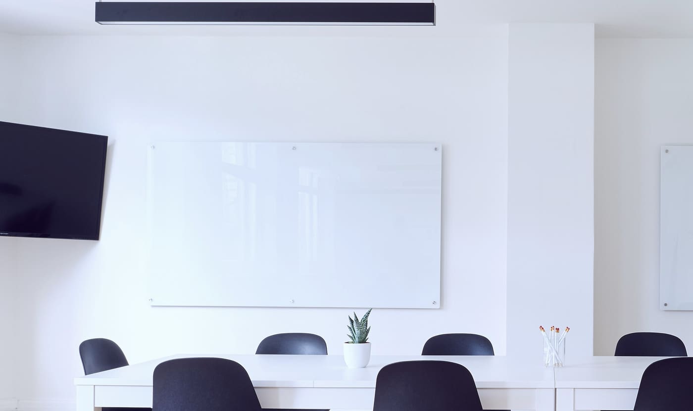 Salle de réunion claire avec un tableau blanc, une grande table et des chaises, où se tiennent les ateliers de cadrage