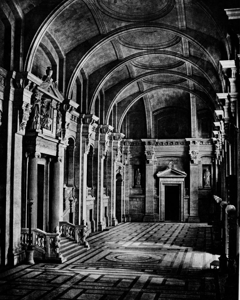La salle des pas perdus d'un palais de justice, voûtes, colonnes et portes monumentales.