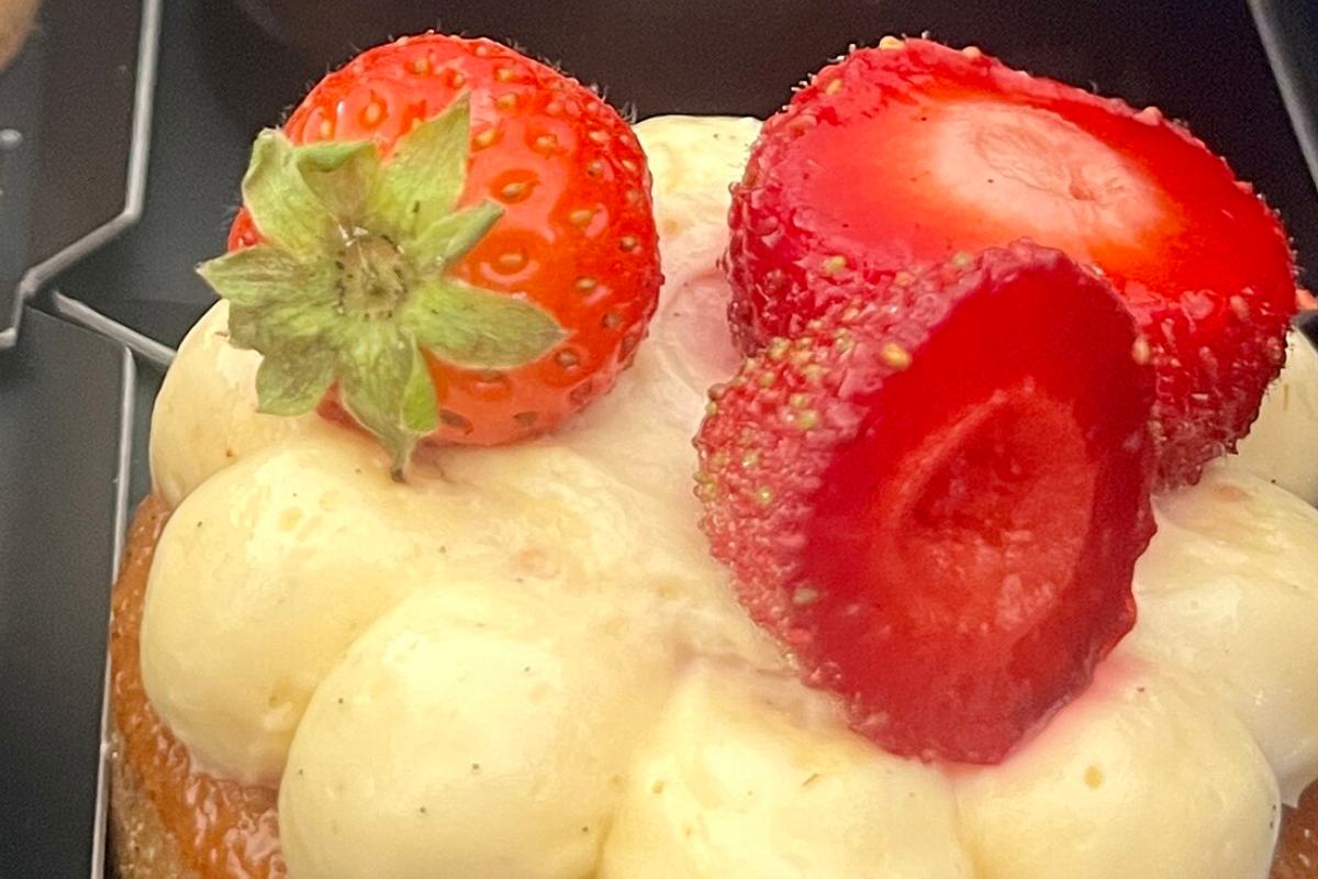 Pâtisserie en vitrine, crème montée et fraises fraîches posées sur le dessus