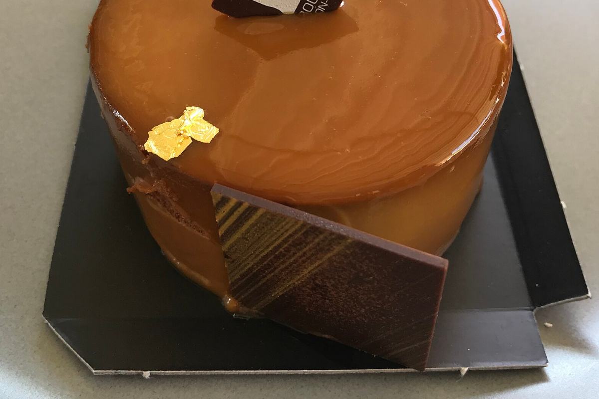 Entremets rond au glaçage caramel brillant, plaque de chocolat sur le côté
