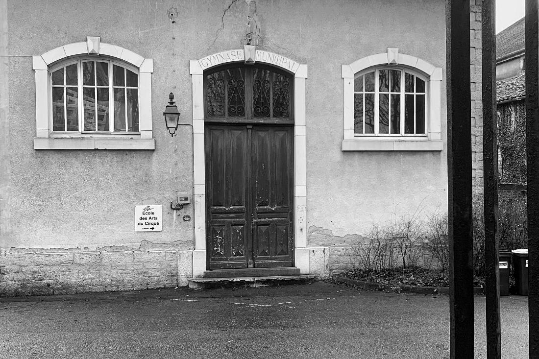 Façade ancienne du local de l'association, grande porte en bois entre deux fenêtres