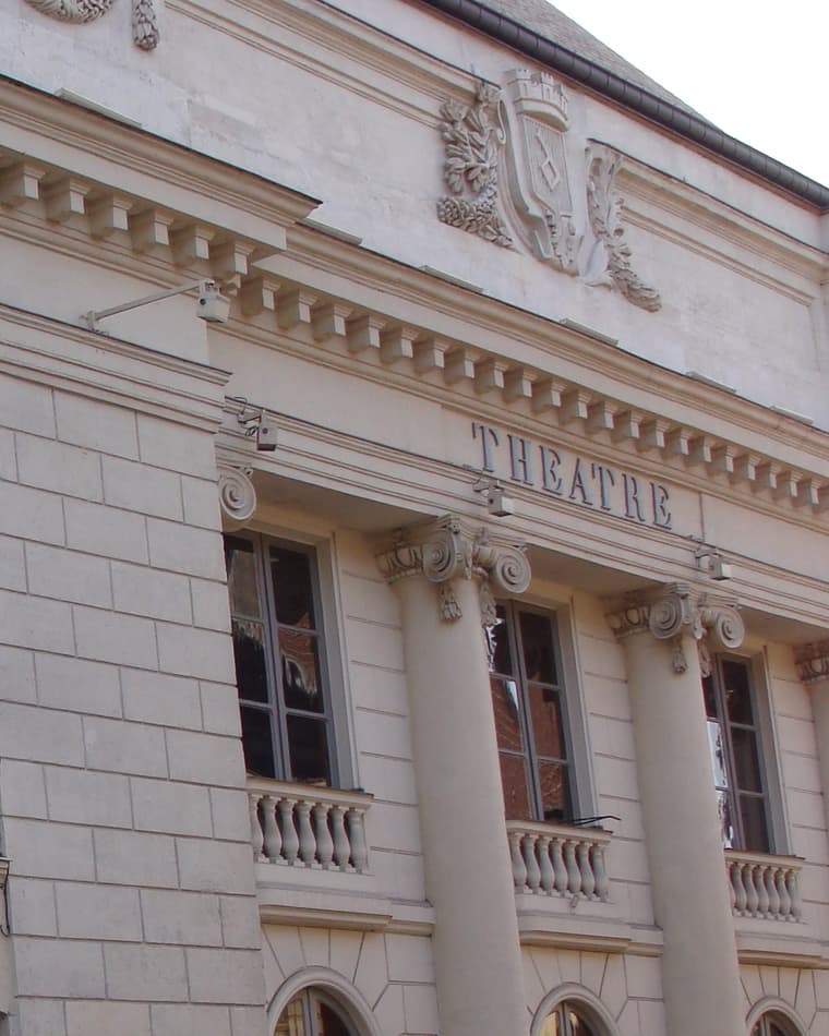 La façade du théâtre, colonnes de pierre et le mot Théâtre gravé sous la corniche
