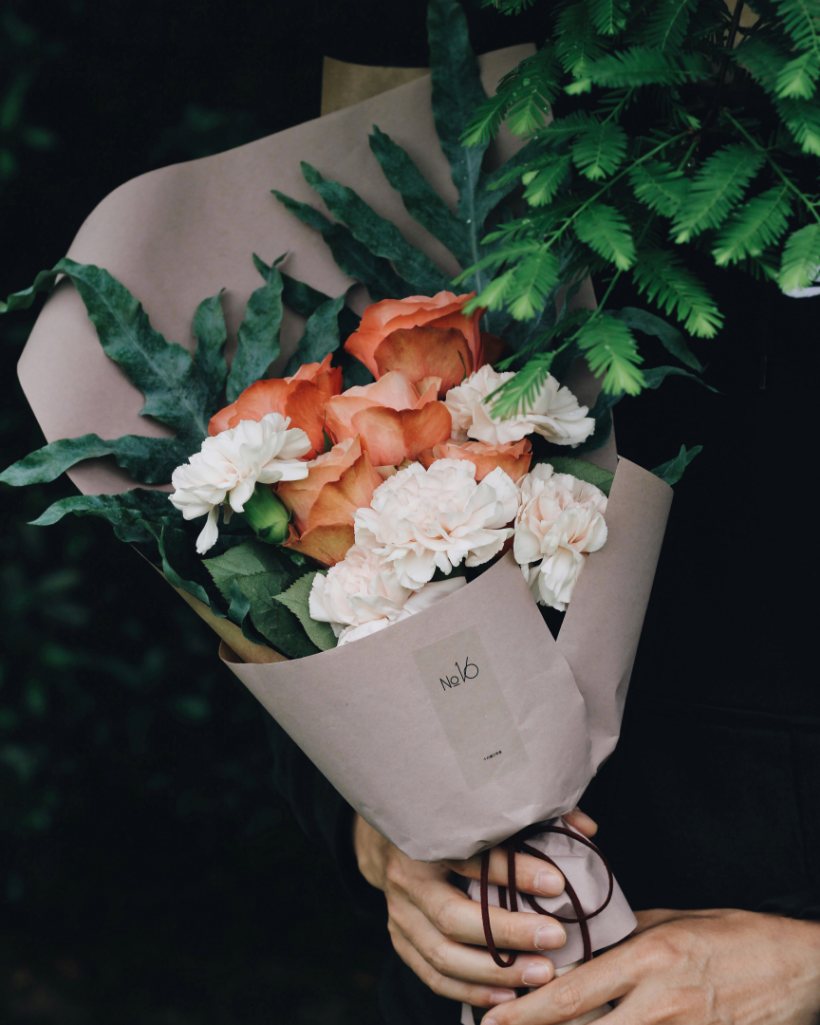 Bouquet du jour emballé dans du papier kraft, roses corail et œillets blancs
