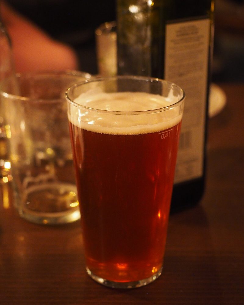Verre de bière ambrée cuivrée posé sur le comptoir en bois