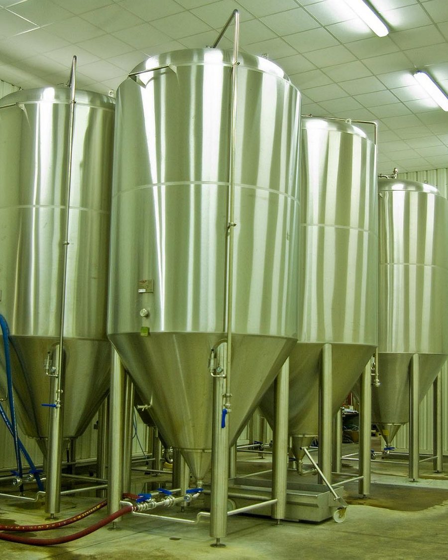 Cuves de fermentation cylindro-coniques alignées dans la salle de garde