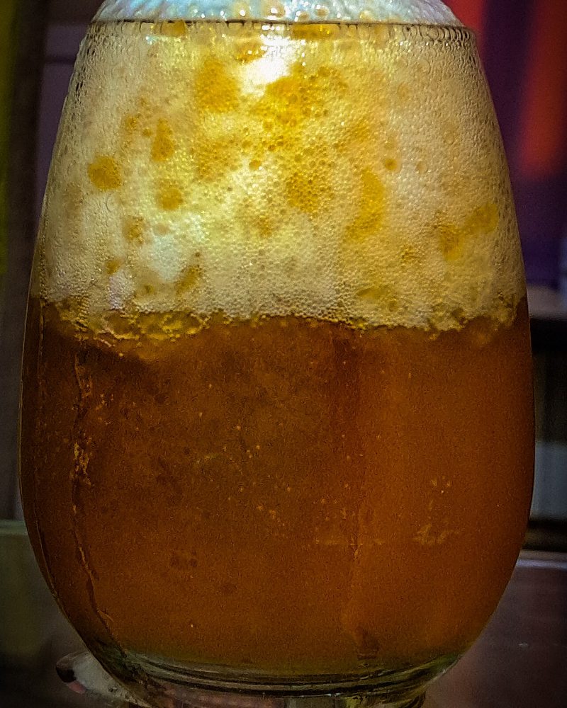 Gros plan sur une bière dorée et sa mousse dense, dans un verre ballon