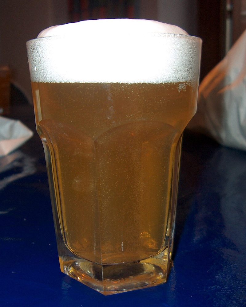 Verre de bière blonde trouble sans alcool, mousse blanche épaisse